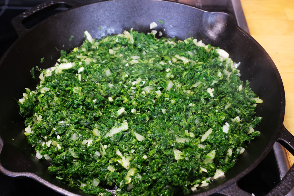 cooking spinach, and onion in a cast iron skillet