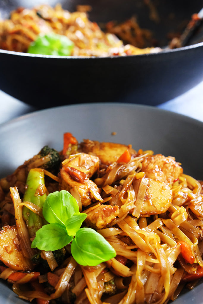 Drunken Noodles with Chicken with a Cast Iron Wok in the background