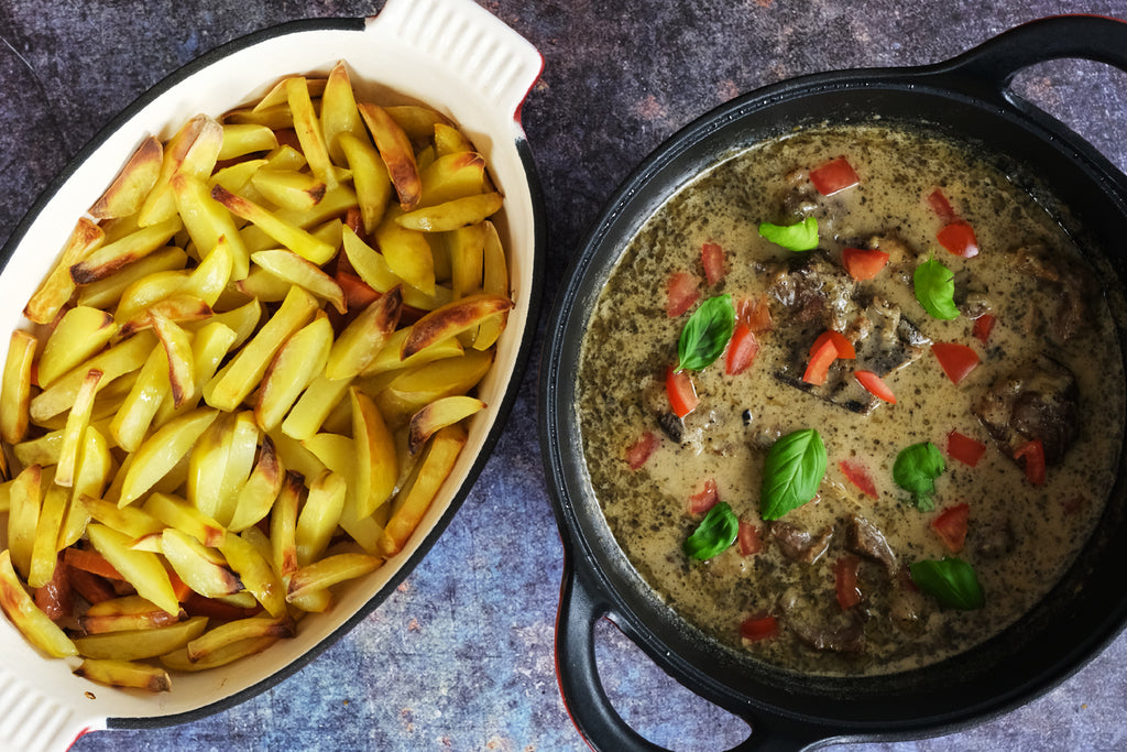 potatoe wedges in a roasting pan and lamb stew in a cast iron balti dish