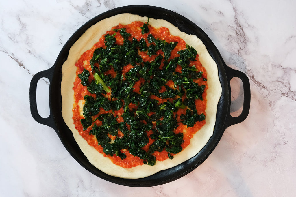 Ajvar relish and kale on the pizza dough