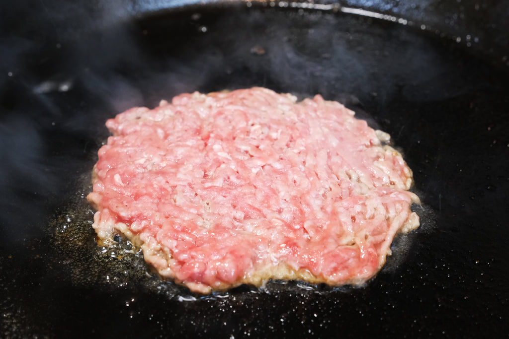 ground beef for a smashed burger in a cast iron skillet
