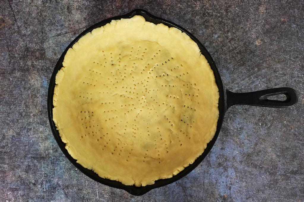 pricked pie dough in a cast iron skillet