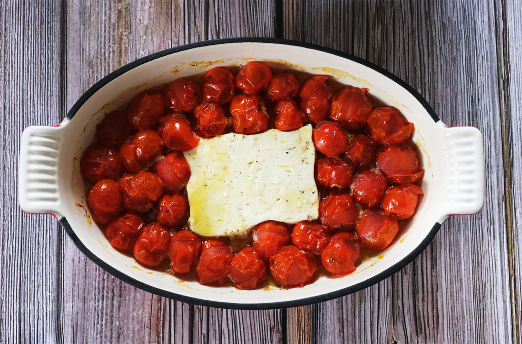 cherry tomatoes and feta in an enameled roasting pan