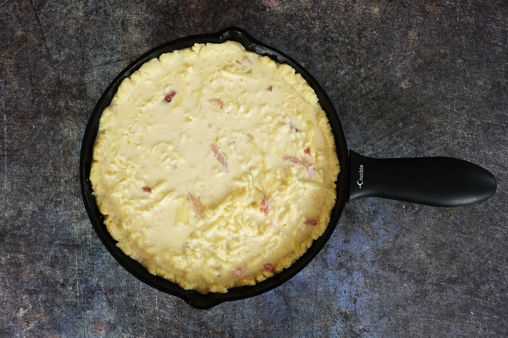 cast iron skillet with Quiche Lorraine ready for the oven