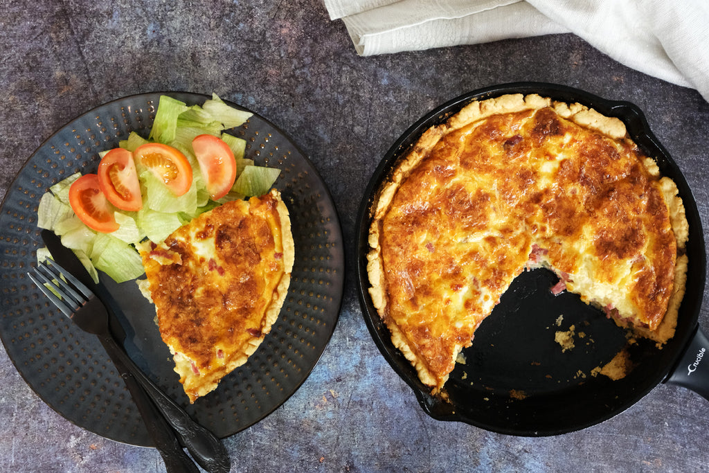 Quiche Lorraine served next to a cast iron skillet with the remaining pie