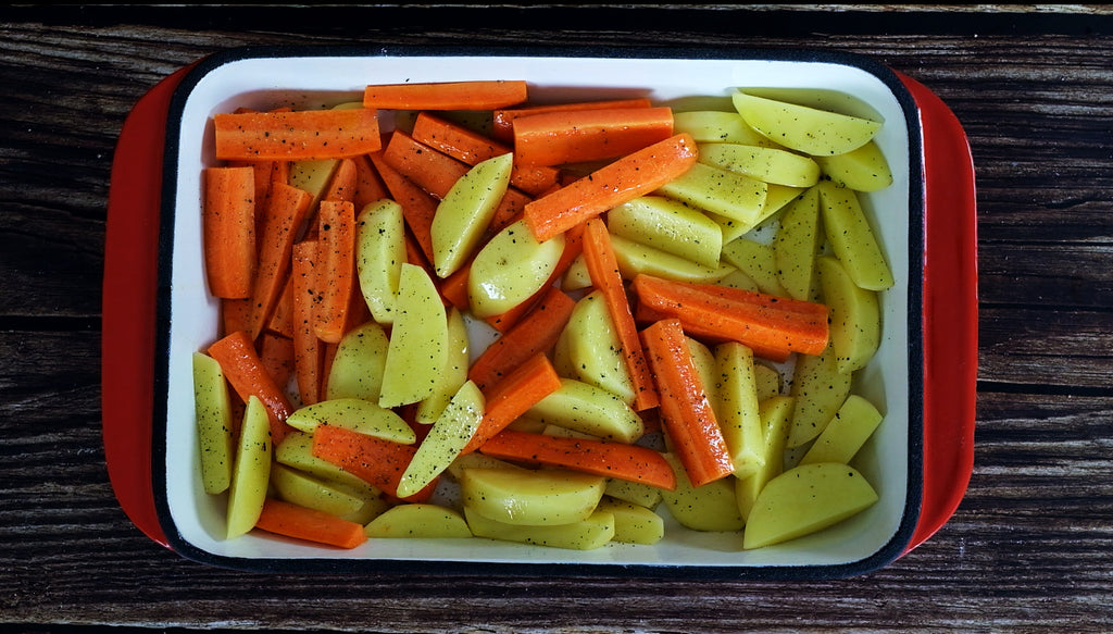 carrots and potatoes in an enemeled cast iron roasting pan