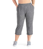 Bottom half of plus size woman wearing JunoActive SoftWik relaxed fit long, heather gray, plus size capris, facing front. Woman has both hands in side pockets.