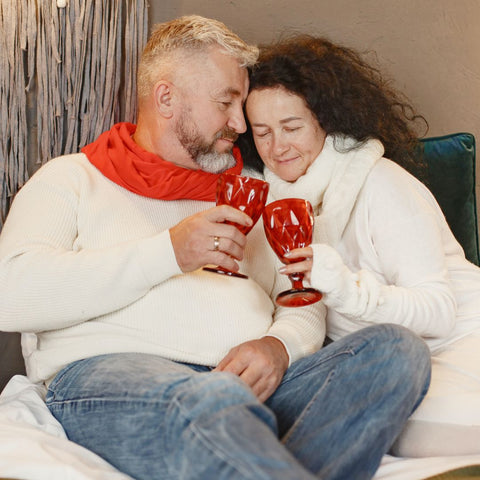 Couple Sharing Drinks While Sitting On Bed