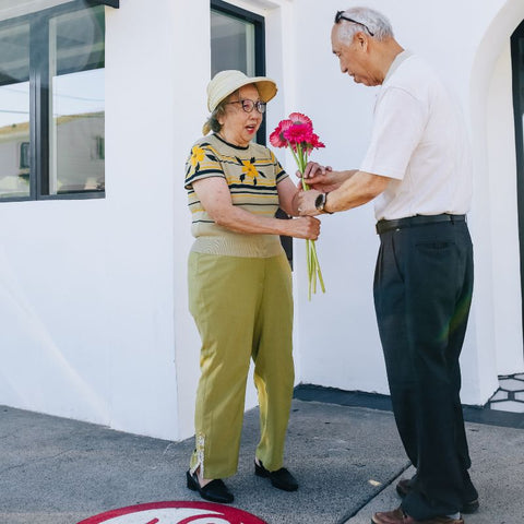 Elderly man giving flowers to wife