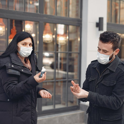 Couple wearing mask and using hand sanitizer to prevent covid spread