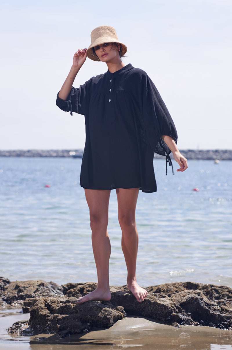 Brunette Model wearing the lady & the sailor Billow Sleeve Mini Dress on the beach in Black Gauze.
