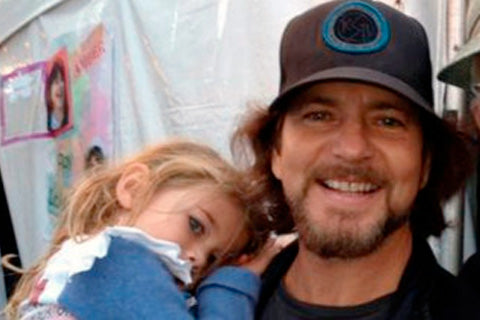 Eddie Vedder, vocalista do Pearl Jam, ostentando seu bon preto de aba curva irado ao lado da sua filha