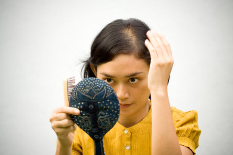 balding woman looking in mirror