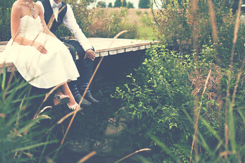 bride and groom sitting on bridge