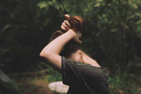 redhead tying hair up in woods