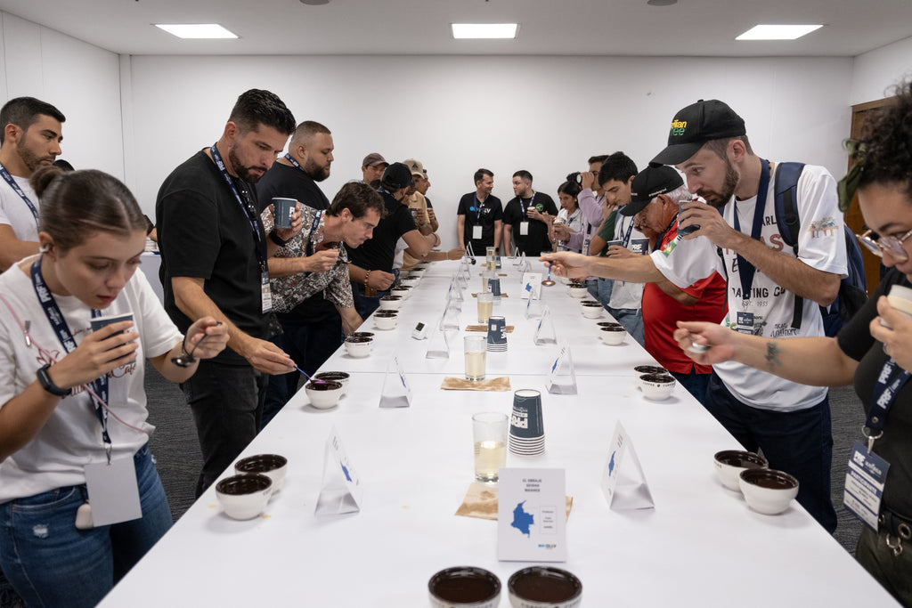 People cupping coffee on both sides of a long white table