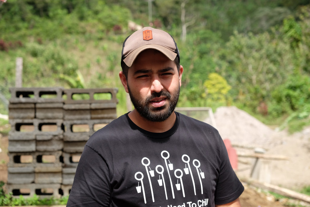 A Honduran man in a black t-shirt with white graphic and a baseball cap