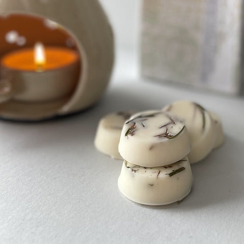 Small pile of wax melts next to a lit oil burner