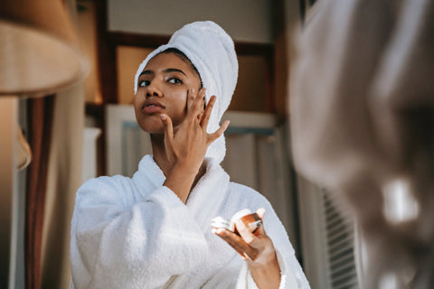 Woman applying moisturiser to her face in a mirror