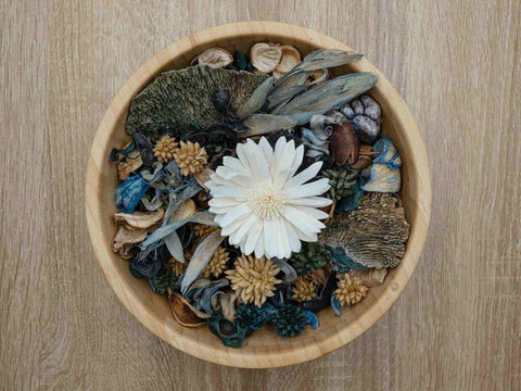 Wooden bowl of potpourri with a white flower in the centre