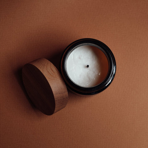 above view of a candle with the lid next to it. brown background