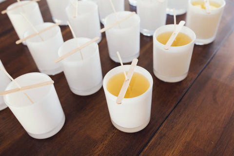 Rows of candles with their wicks being held up on a wooden table