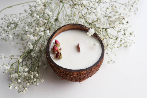 Coconut candle centre frame with white botanicals around it, some rosehips placed onto the solidified wax. The candle has a wooden wick