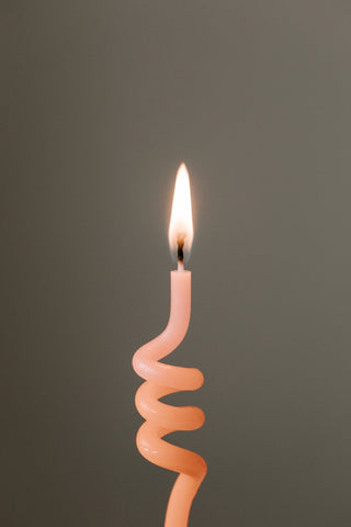 Thin pink lit candle that looks a bit like a curly straw