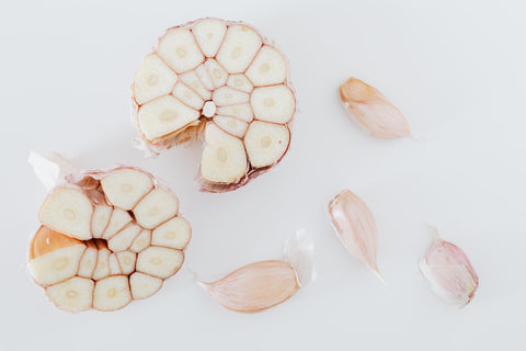 bulb of garlic cut in half with 4 single cloves around the cut bulb