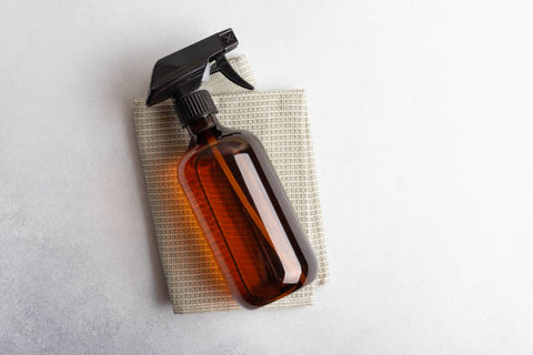 Amber glass spray bottle laid on a small flannel