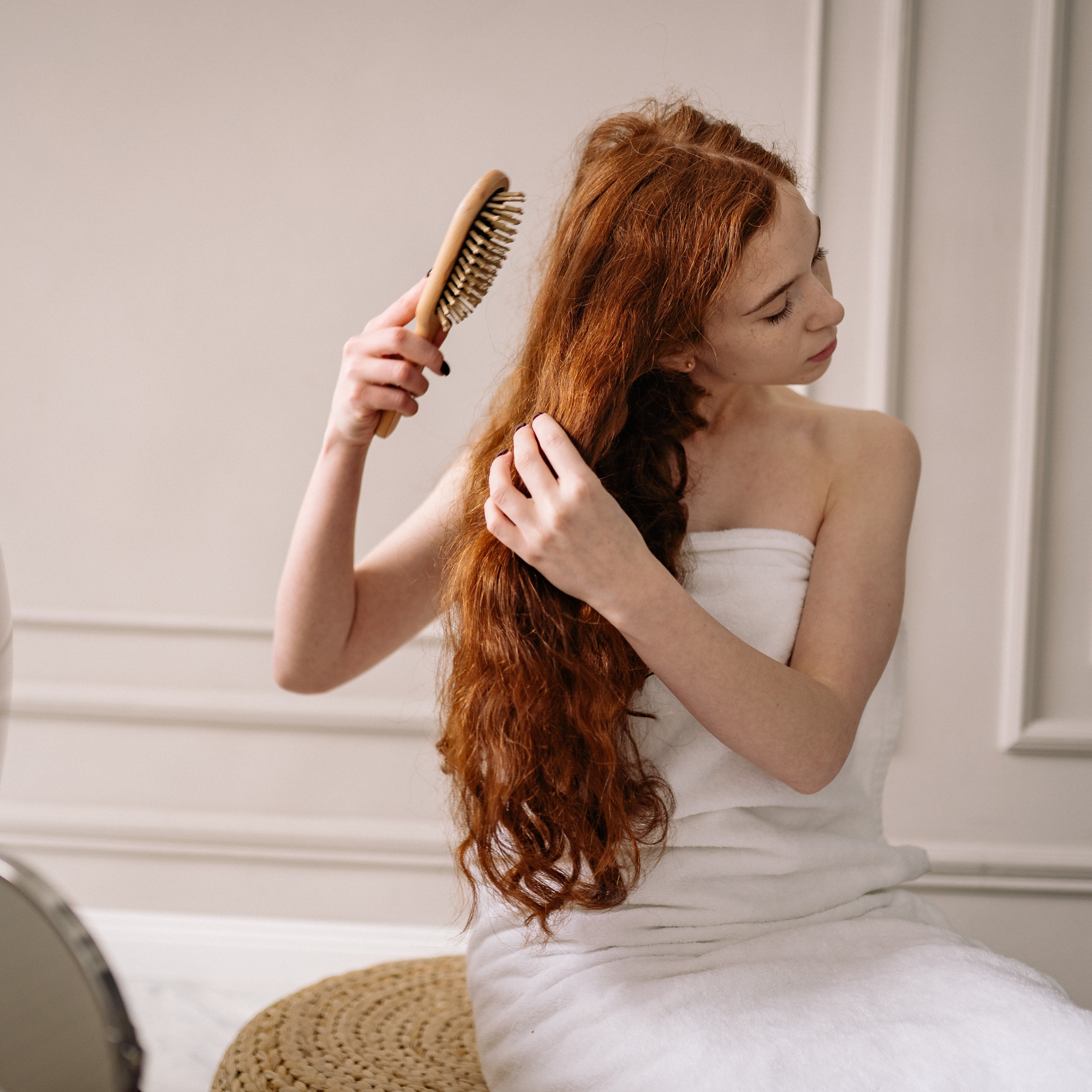 Woman combing through her ginger hair.