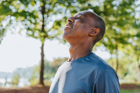 Happy man taking a deep breath outside