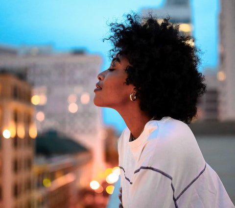 Woman breathing out a sigh of relief looking out over a city