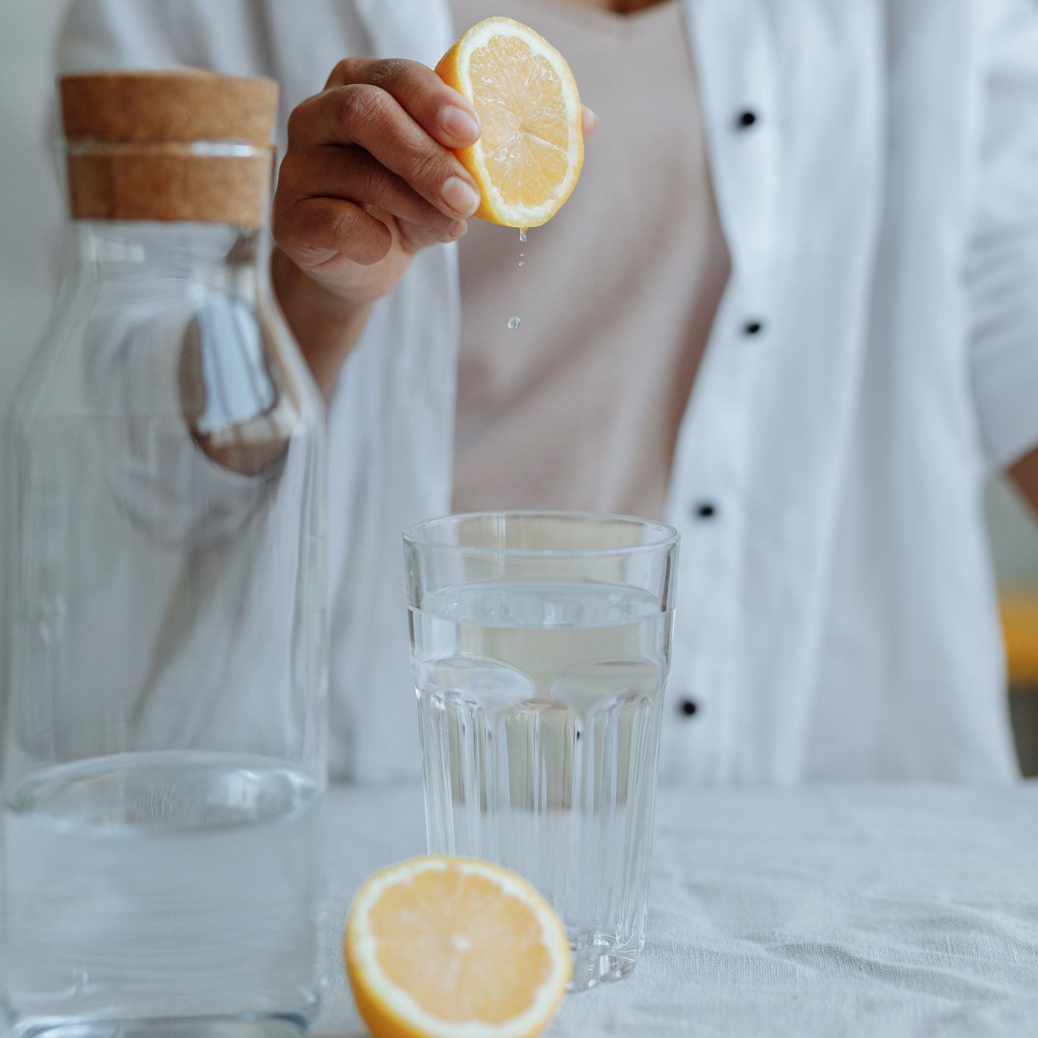 Woman squeezes lemon into glass, with beaker in the foreground
