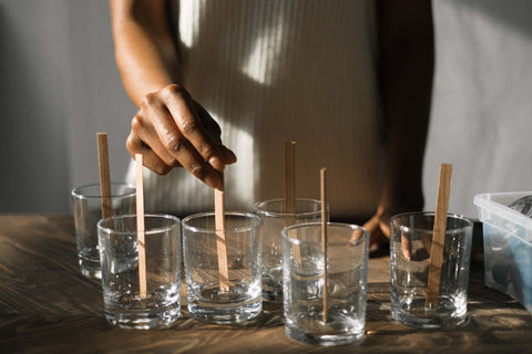 Woman putting wooden sticks into empty glass candle holders