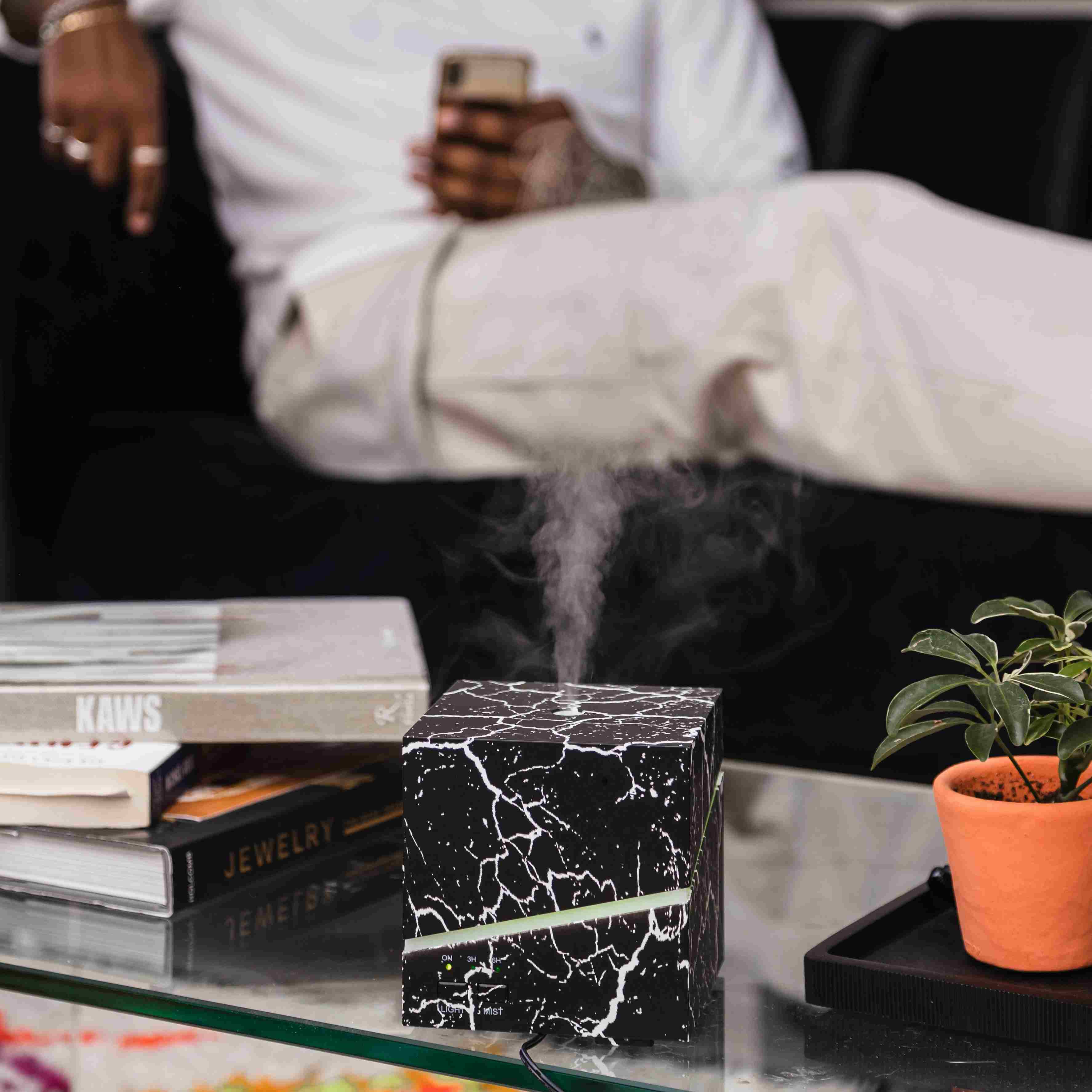 Diffuser emitting steam with person sat in the background.