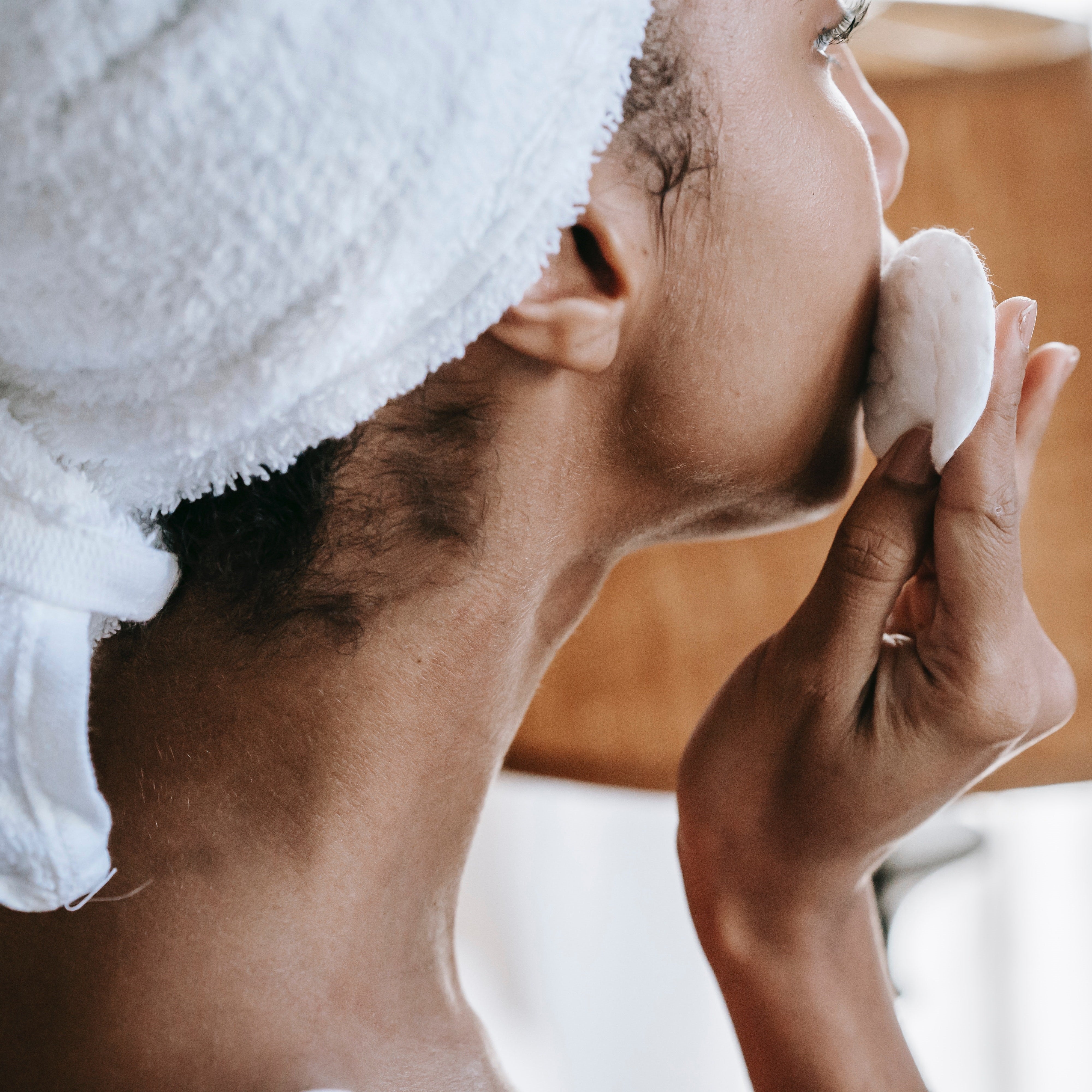 Woman cleaning face with cotton pad