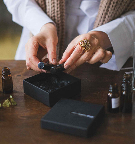 A woman packaging perfume into a small black box