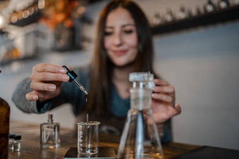 Woman using a dropper to put fragrance into a small beaker