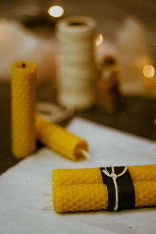 Beeswax candle sticks, two are wrapped in a piece of black paper and tied with string