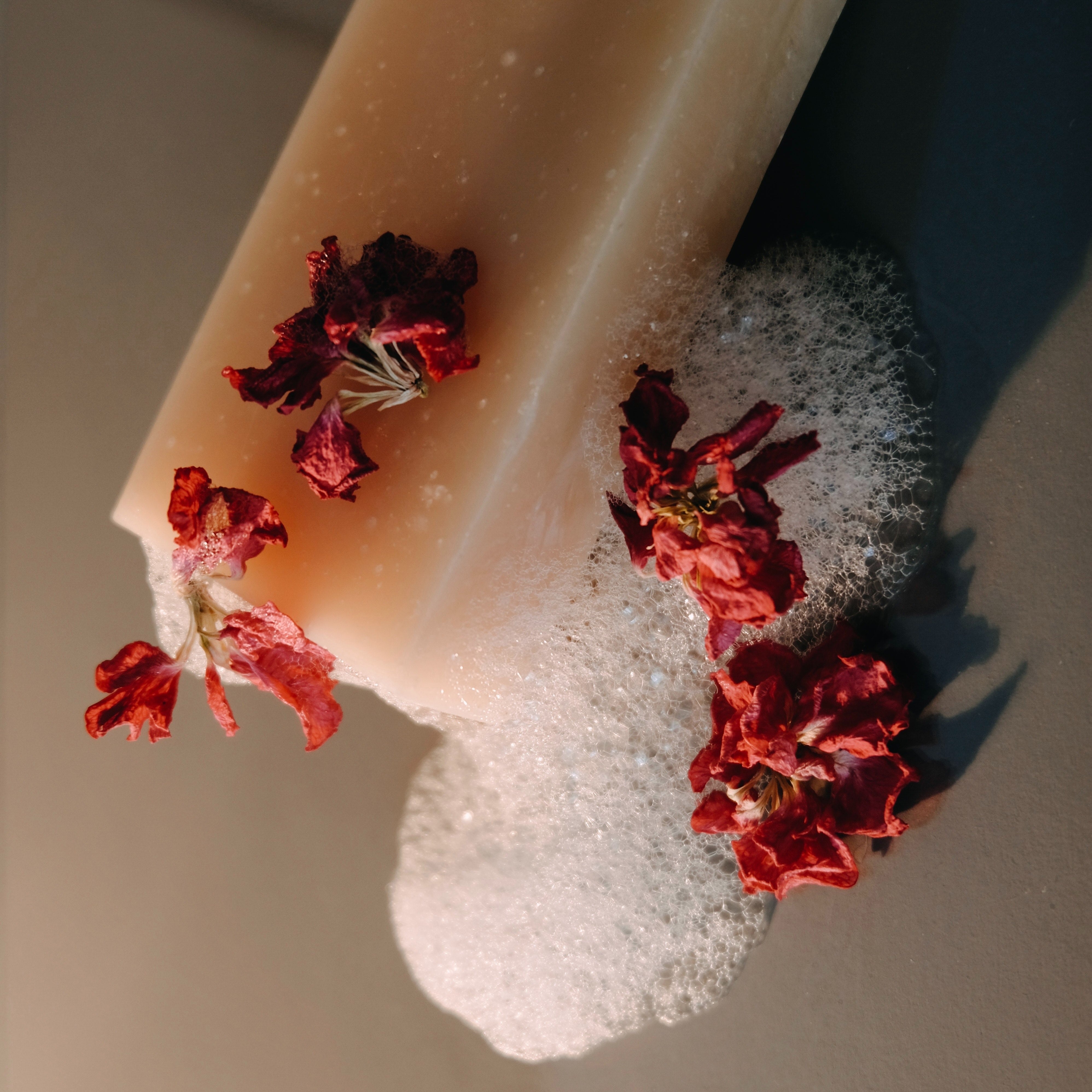 Cream coloured soap surrounded by lather and flowers.