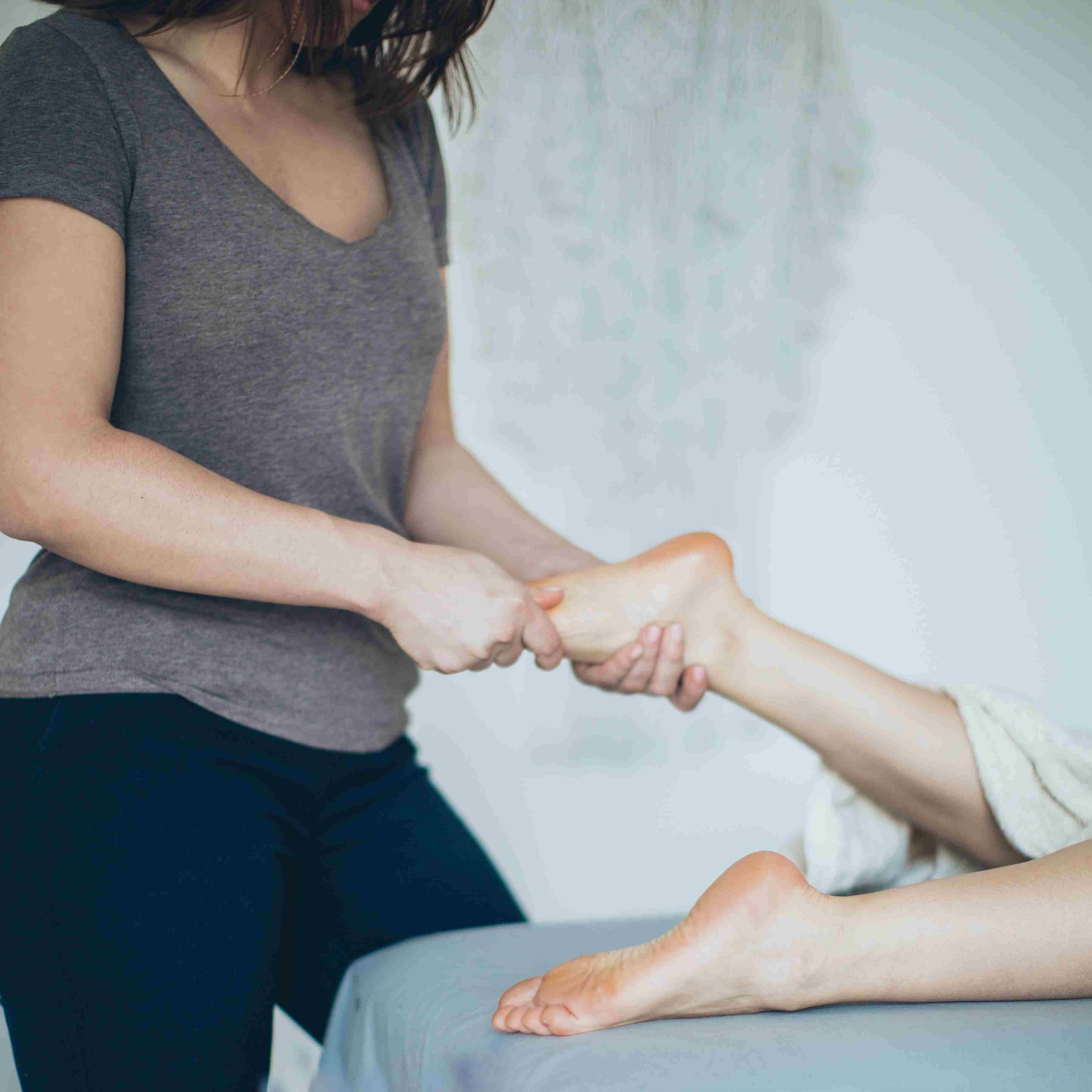 Woman performing a foot massage on person.