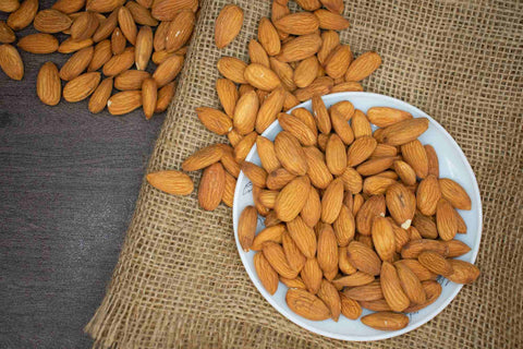 Almond spilling out of a bowl onto a rustic table cloth