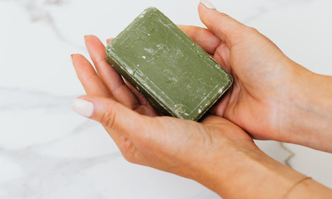 Green soap bar in two hands