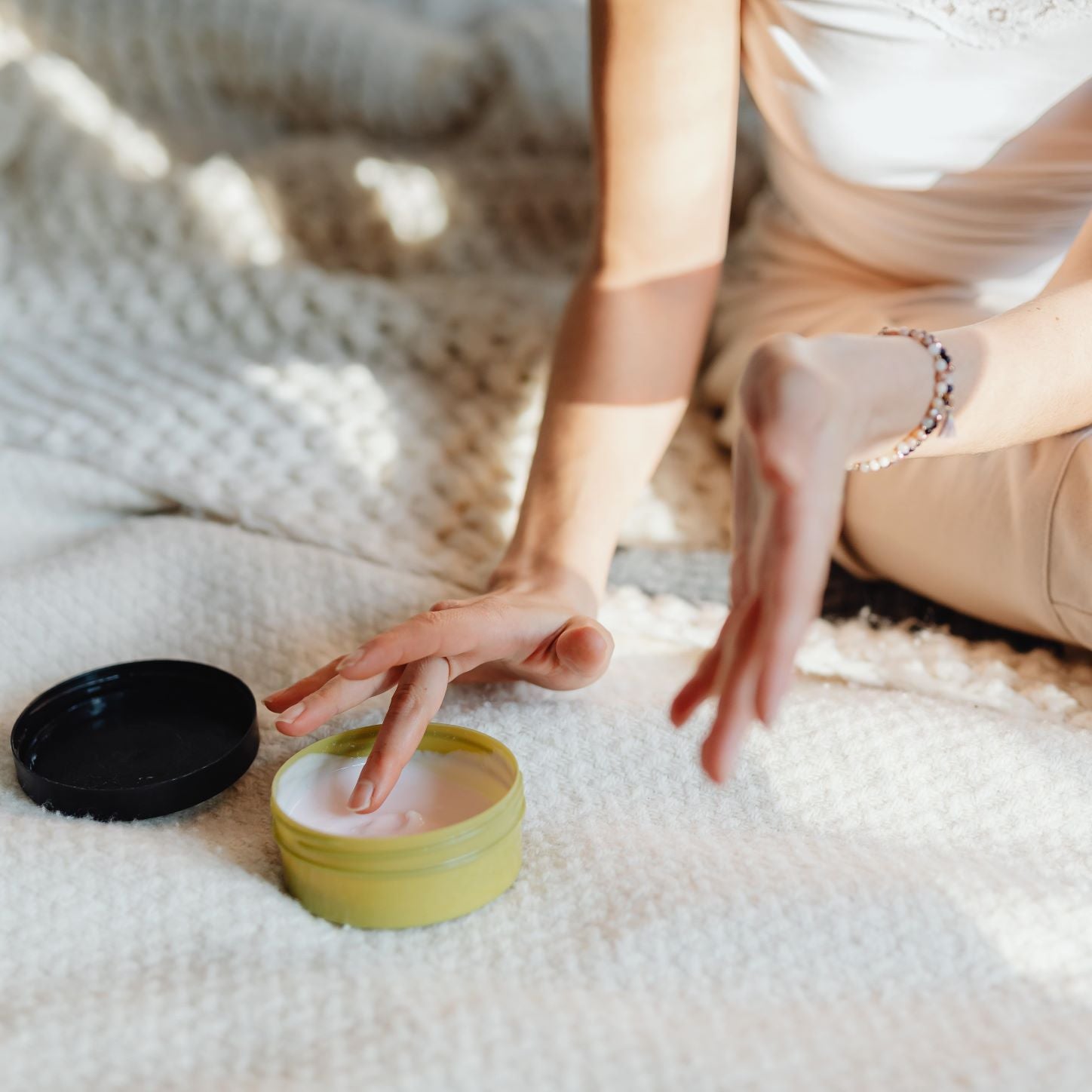 Woman scooping body butter out from a tub.