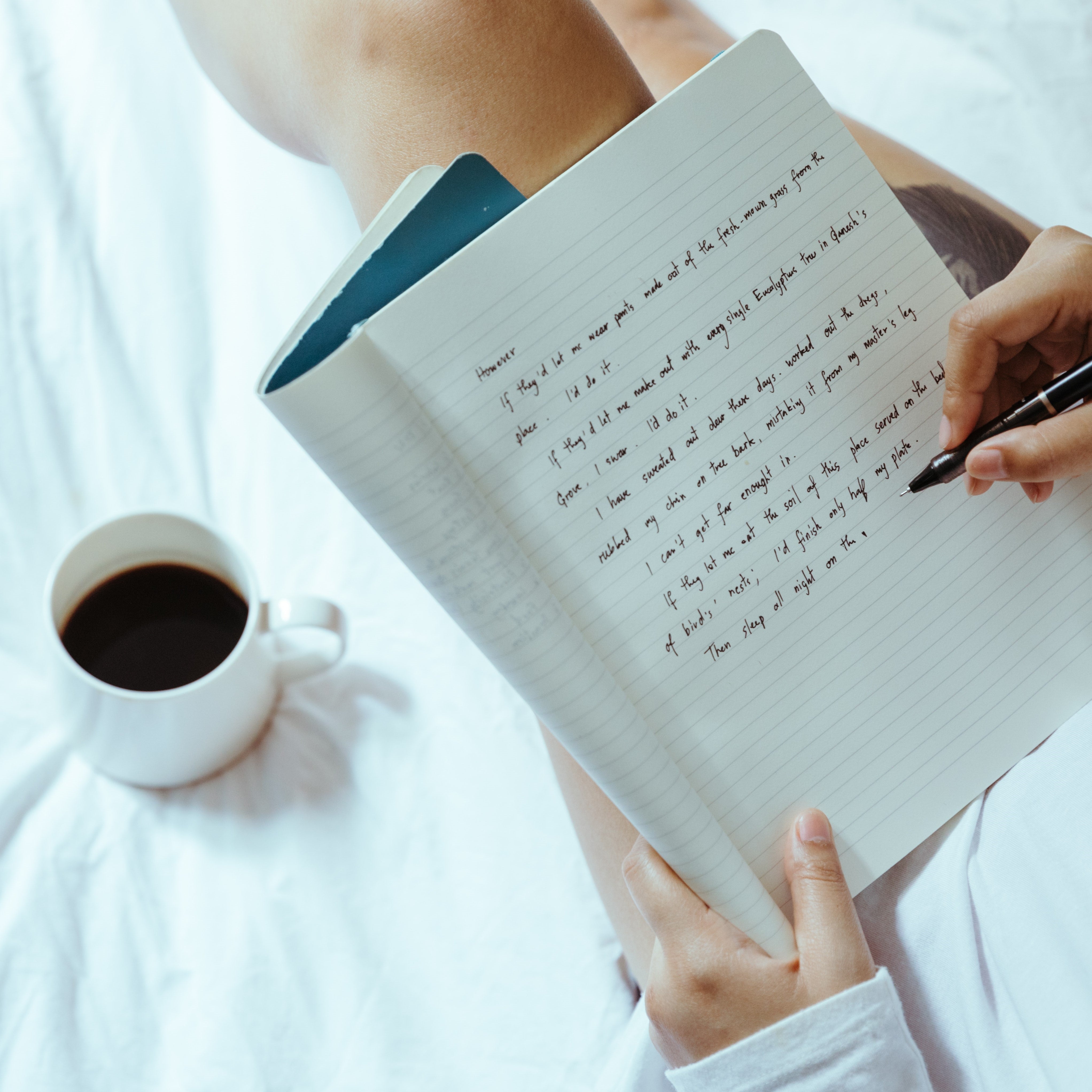 Person making notes whilst drinking coffee