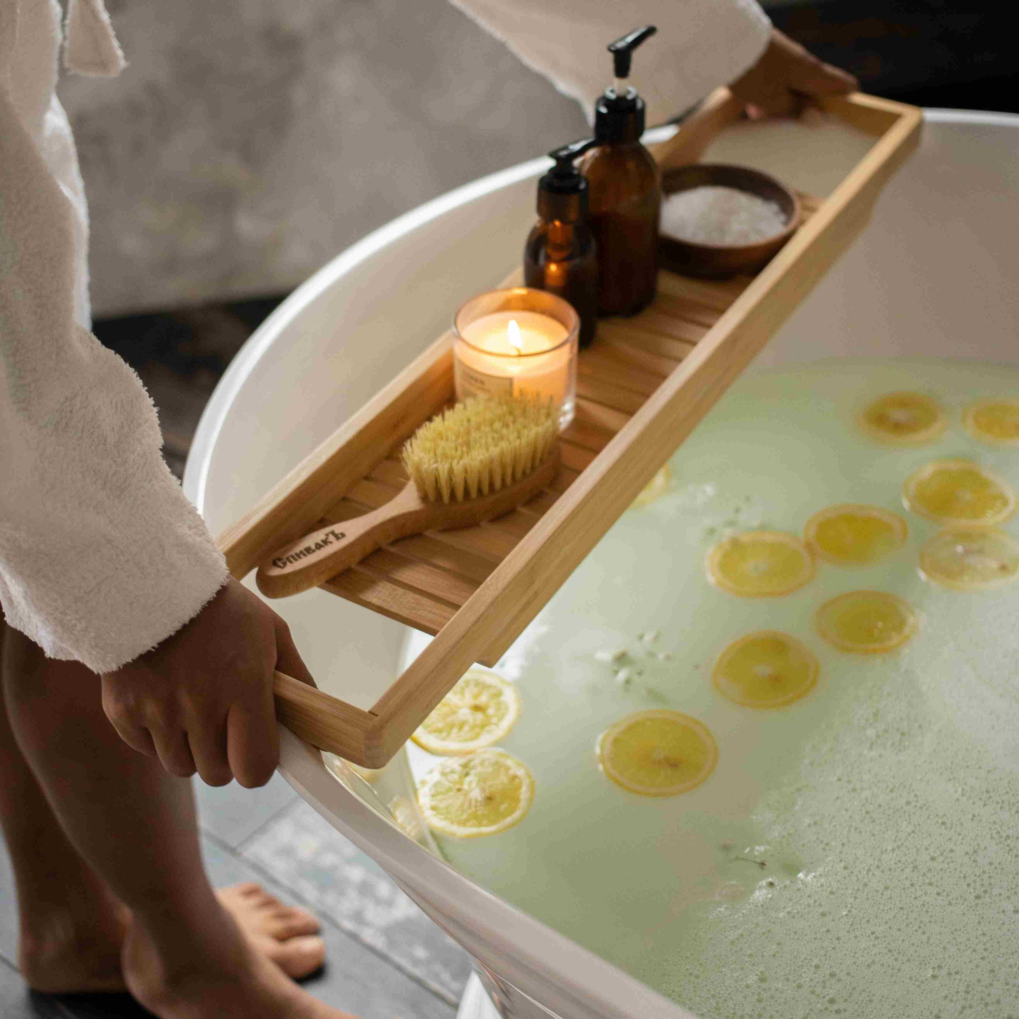 lemon slices in a bath and woman putting down a wellness tray.