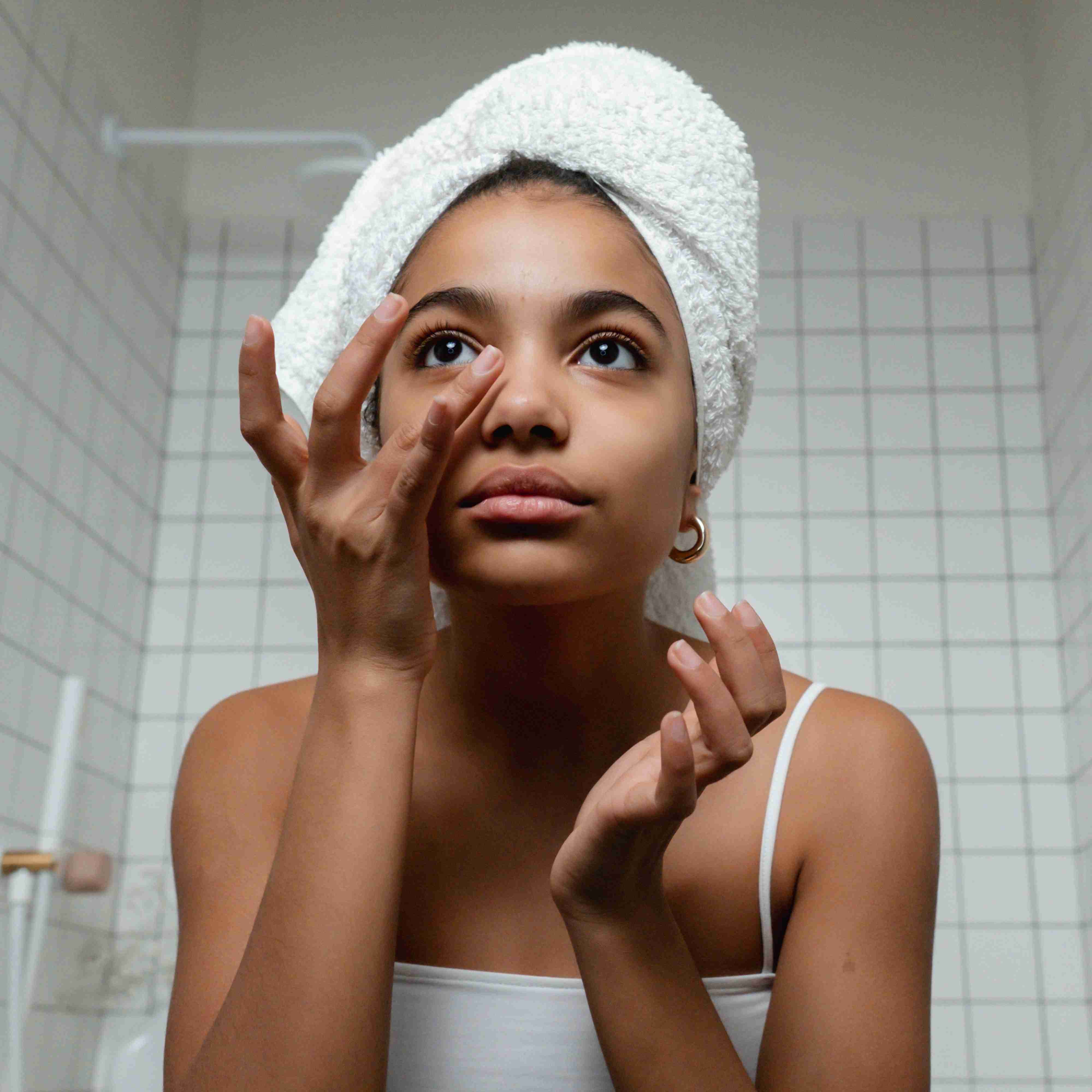 Woman doing her skincare with a towel on her head.