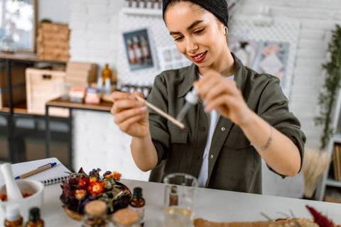 Woman using a dropper to put perfume onto a scent stick to smell test it