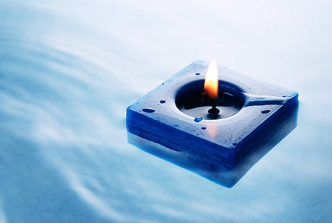 Square blue floating candle in very blue water